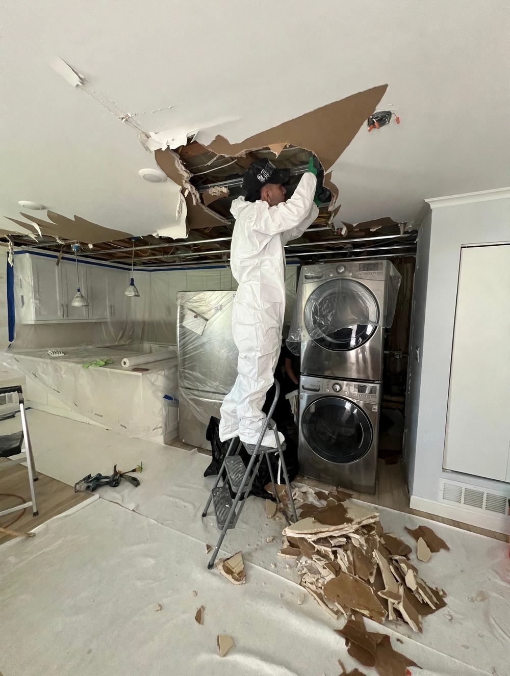 Mitigation worker opening a water-damaged ceiling.