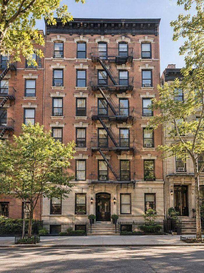 Prewar brick walk-up apartment building with fire escapes.