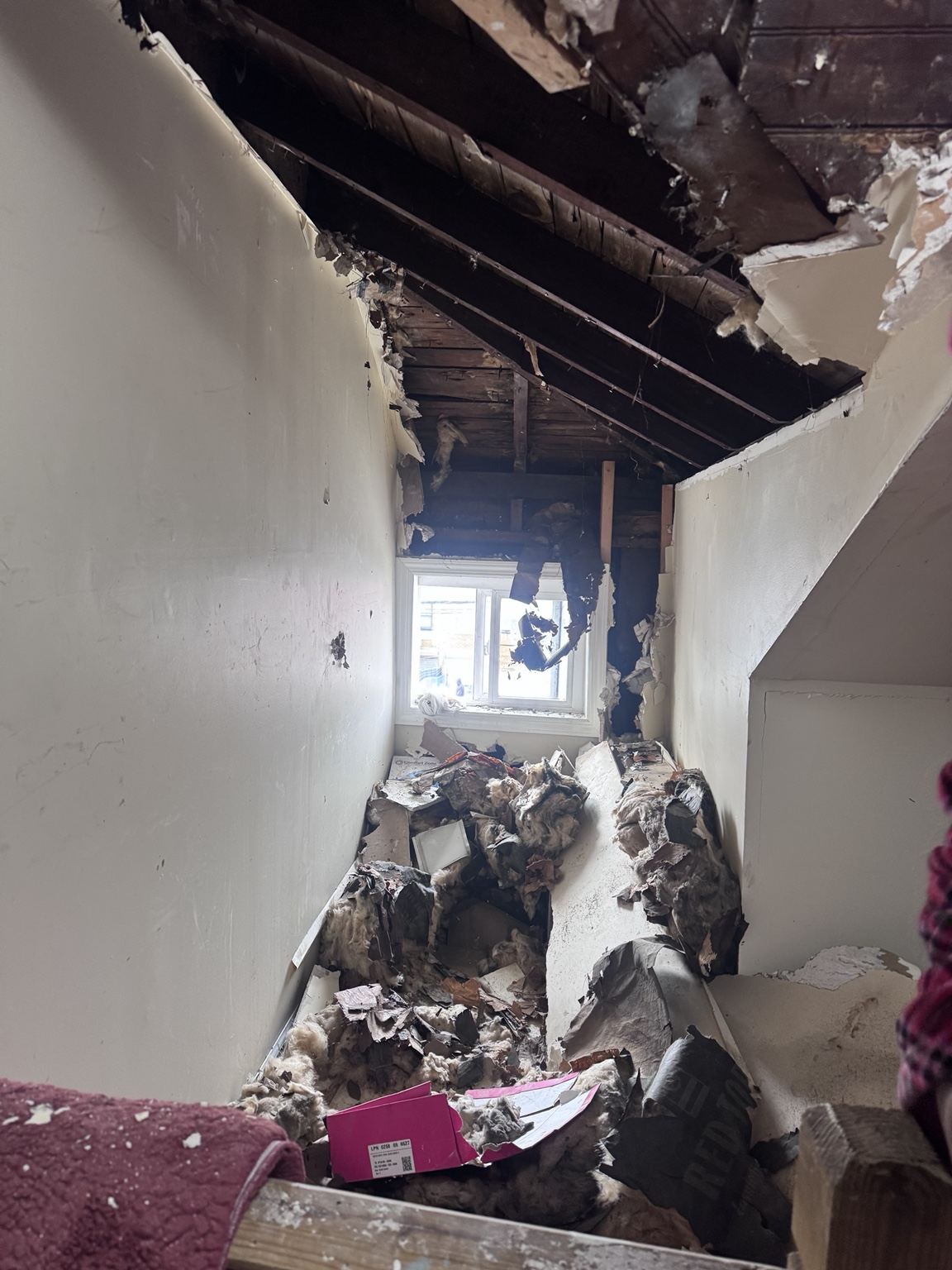 Fire-damaged interior with exposed ceiling framing and debris