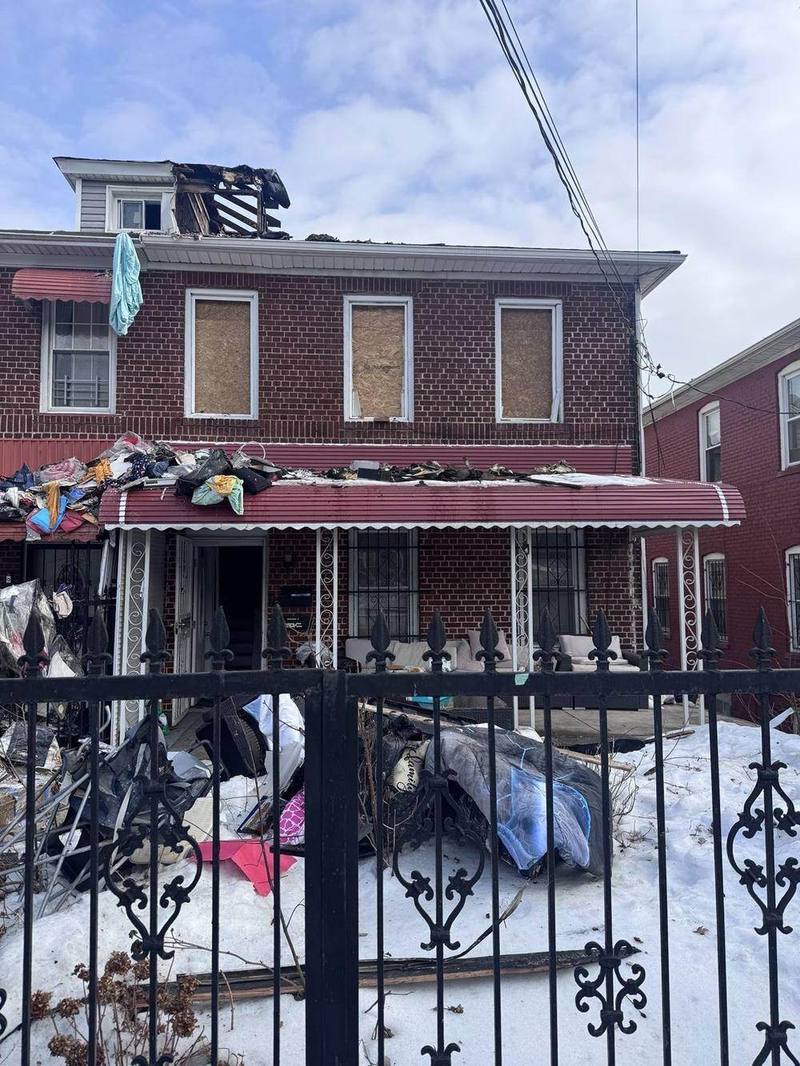 Brick home with fire-damaged roof framing and boarded windows
