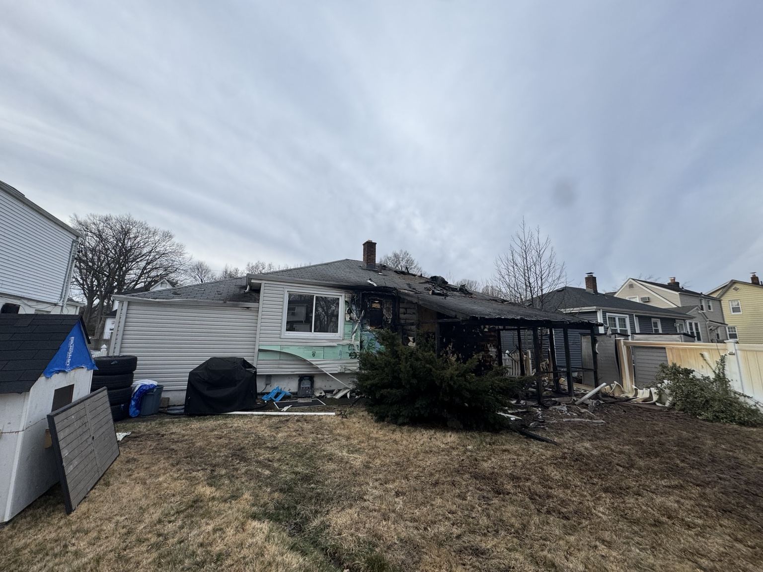 Rear of a fire-damaged house showing roof and exterior damage