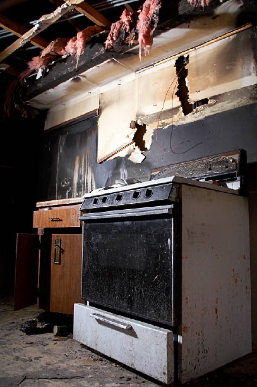 Fire-damaged kitchen with charred walls and a collapsed ceiling.