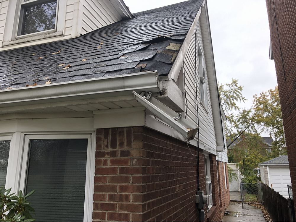 Roof shingles and gutter torn by a storm.