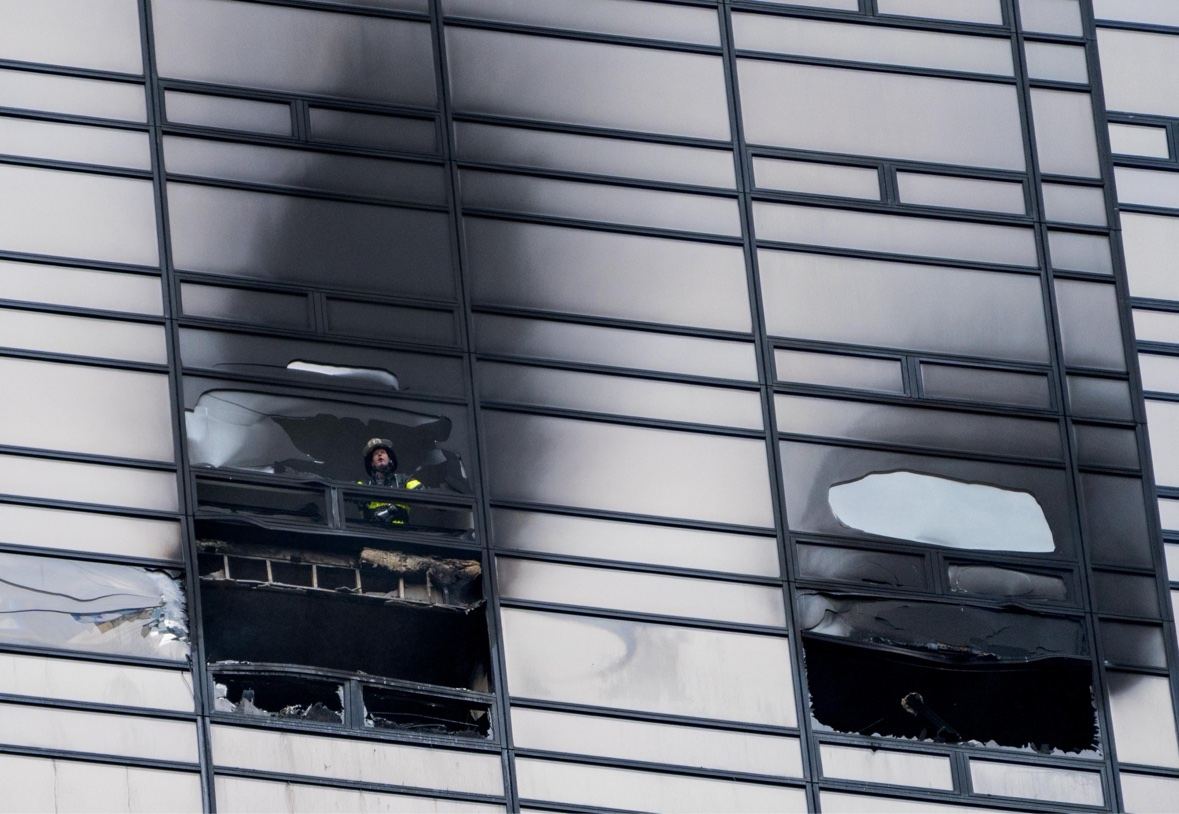 Firefighter at a fire-damaged high-rise window.